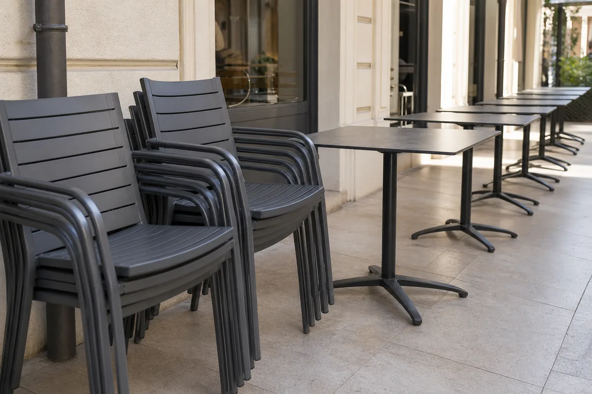 Mobilier de terrasse professionnel en aluminium, chaises empilables et tables alignées le long d&rsquo;une façade