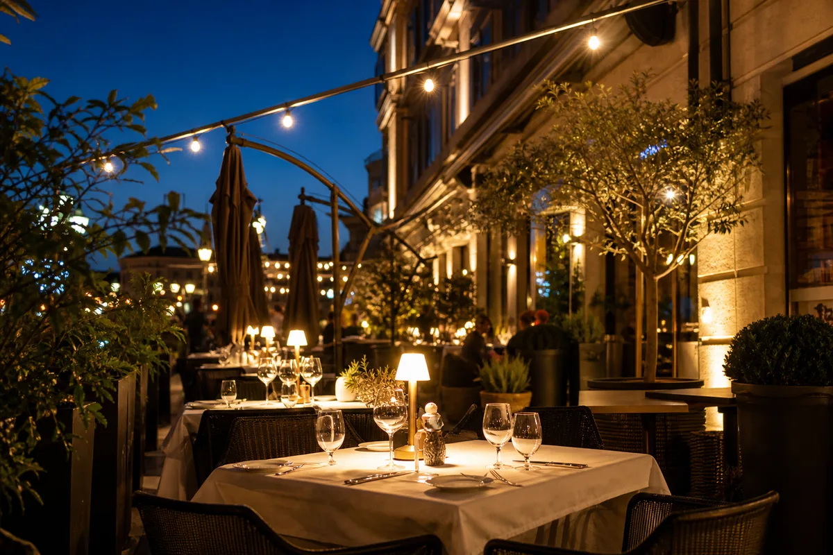 Terrasse de restaurant animée en soirée, tables dressées et éclairage chaleureux à la tombée du jour