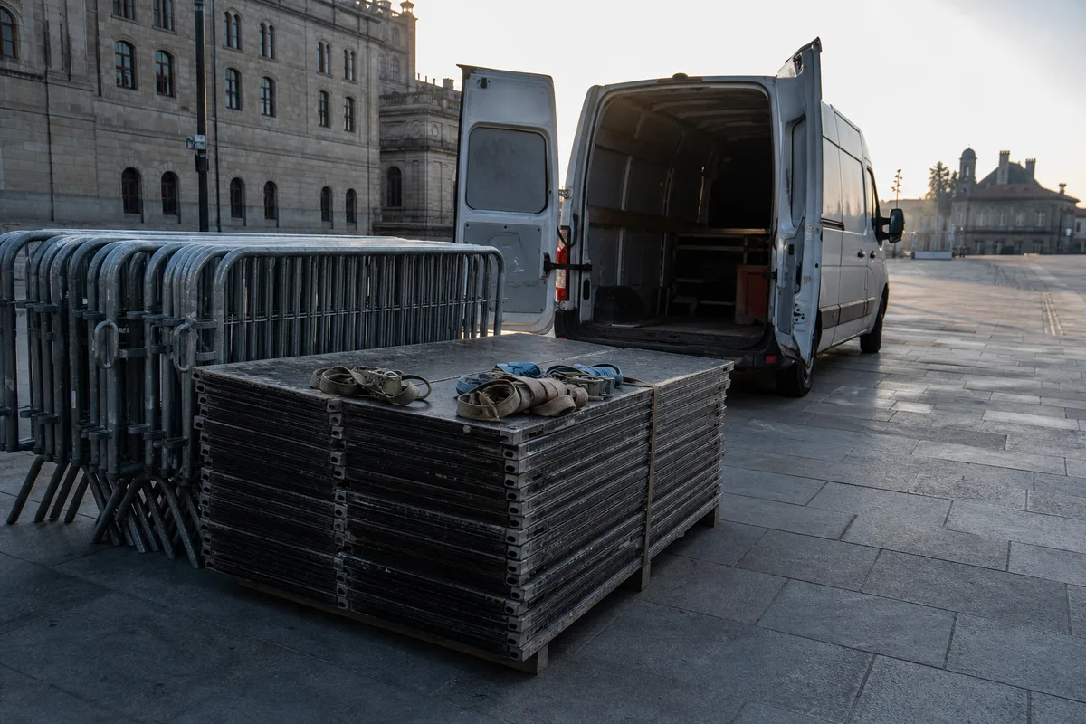 Éléments de plancher et barrières empilés au sol près d&rsquo;un utilitaire ouvert, tôt le matin sur une place
